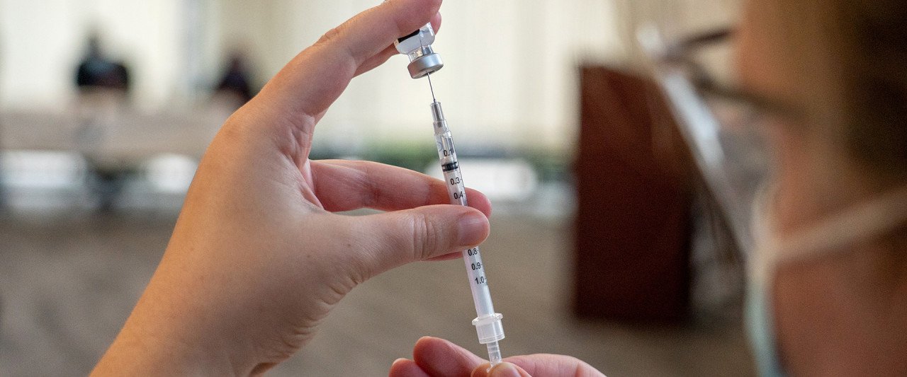 nurse filling syringe with vaccine dose