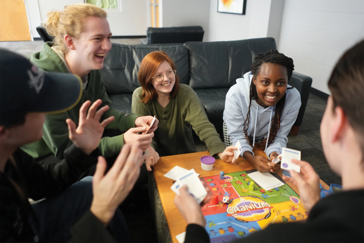 Several students playing a board game. A place to belong on campus.