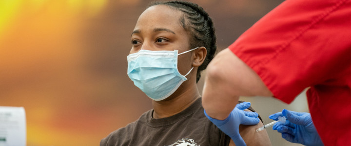 A student wearing a mask getting a vaccine.