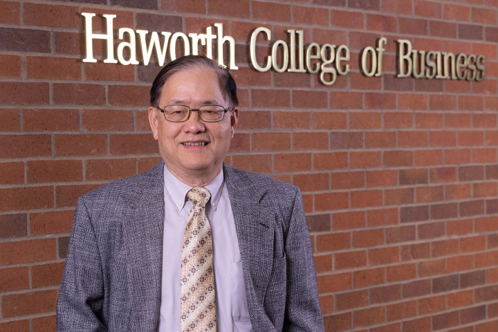 Dr. Bernhard Han, 2023 Fulbright Specialist Award recipient, stands in front of a sign for the Haworth College of Business. He is wearing a grey suit jacket and gold tie.