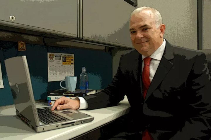 Dr. K.C. O'Shaughnessy sitting at his office desk with a laptop.