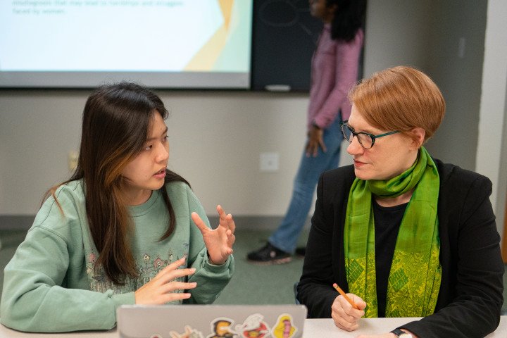 Student and professor talking, in a study area or classroom.