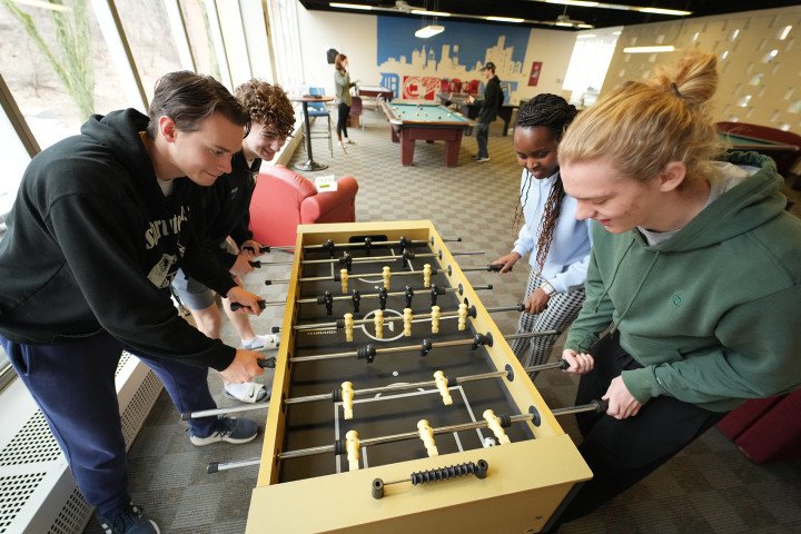 Students, in the Valley's enjoying table hockey in a common space.