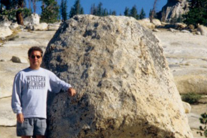 Dane Alexander posing next to a large boulder
