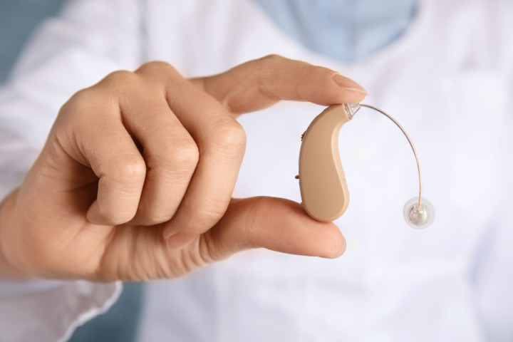 Fingers holding hearing aid