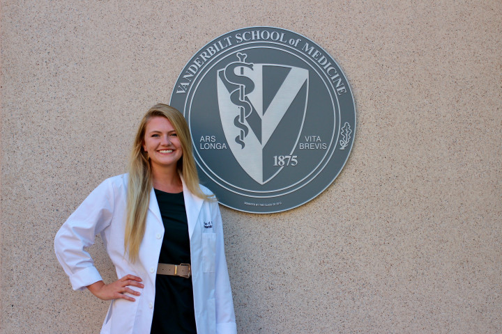 Megan Stanchfield standing next to the Vanderbilt University School of Medicine logo.