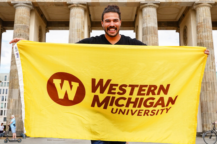 A student holding a WMU flag in Germany.