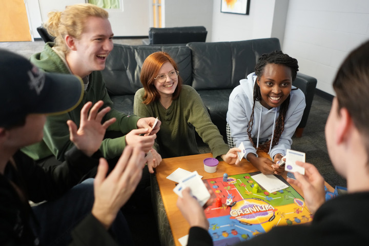 group of students, playing a board game, in the common space in the Valley's.