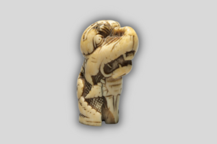 A twelfth-century ivory carving of a dragon's head with teeth bared.