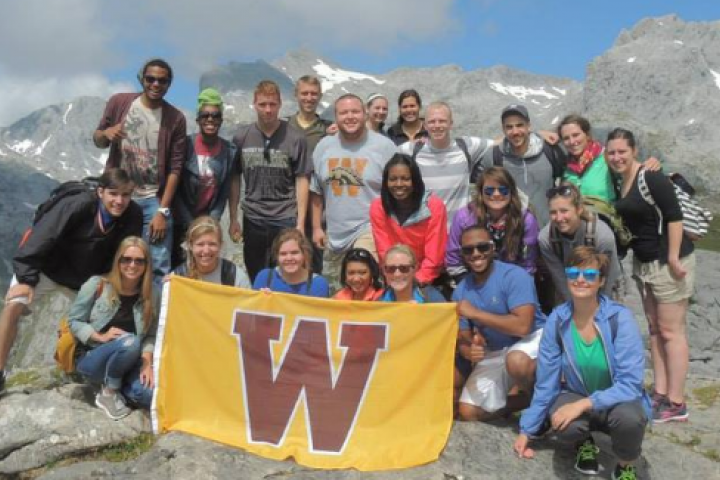 Students gathered together outdoors with the "W" Western Flag