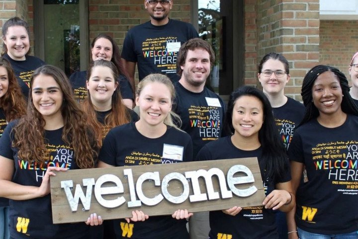 Students holding a "Welcome" sign