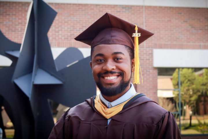 Photo of Justin Scott in an undergraduate cap and gown