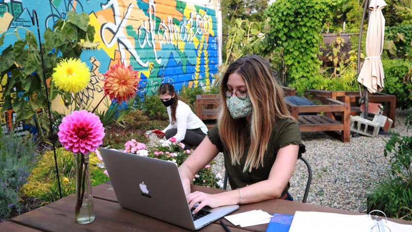 Ariel and Anezka working outside, wearing face masks, in front of Kalamazoo mural
