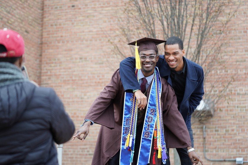 A graduate poses in his regalia with a loved one.