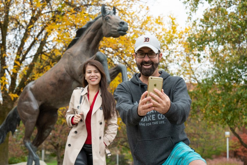 People take a selfie near the Bronco statue.