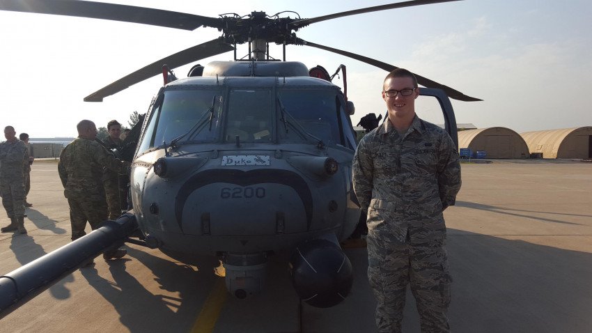 Russell Pliley stands next to a military helicopter.