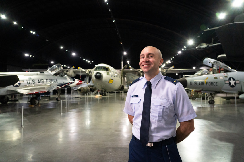 Lt. James Mostek poses in front of old military aircraft.