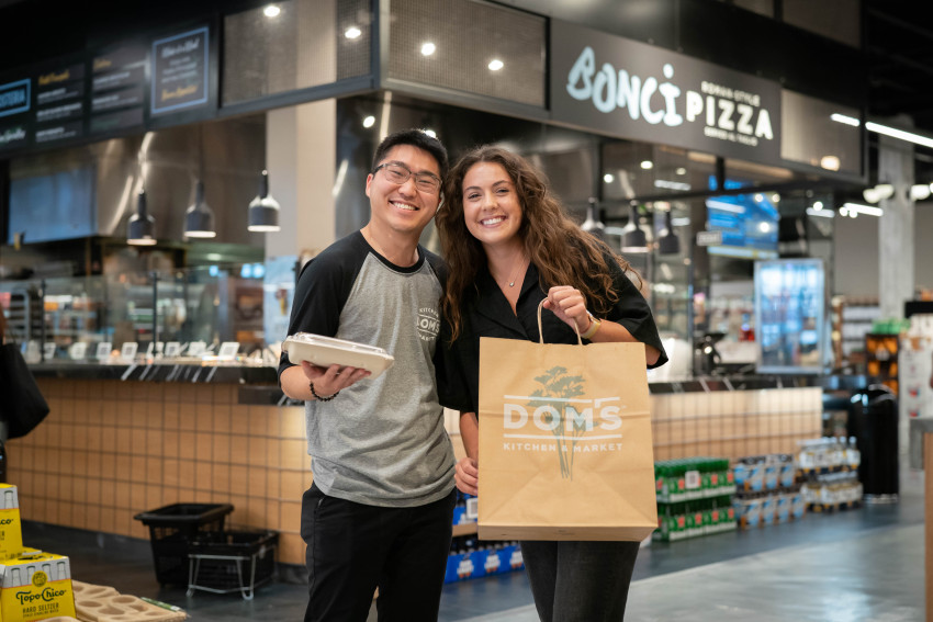 Dominic Gee and Korina Luco hold packages of food at Dom's Kitchen &amp; Market.