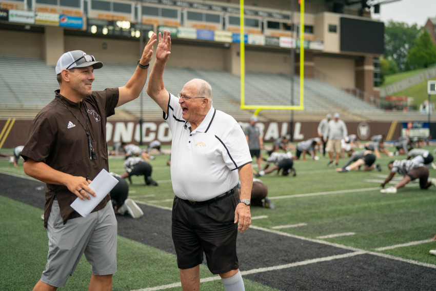 Tim Lester gives Bill Thompson a high five on the football field.