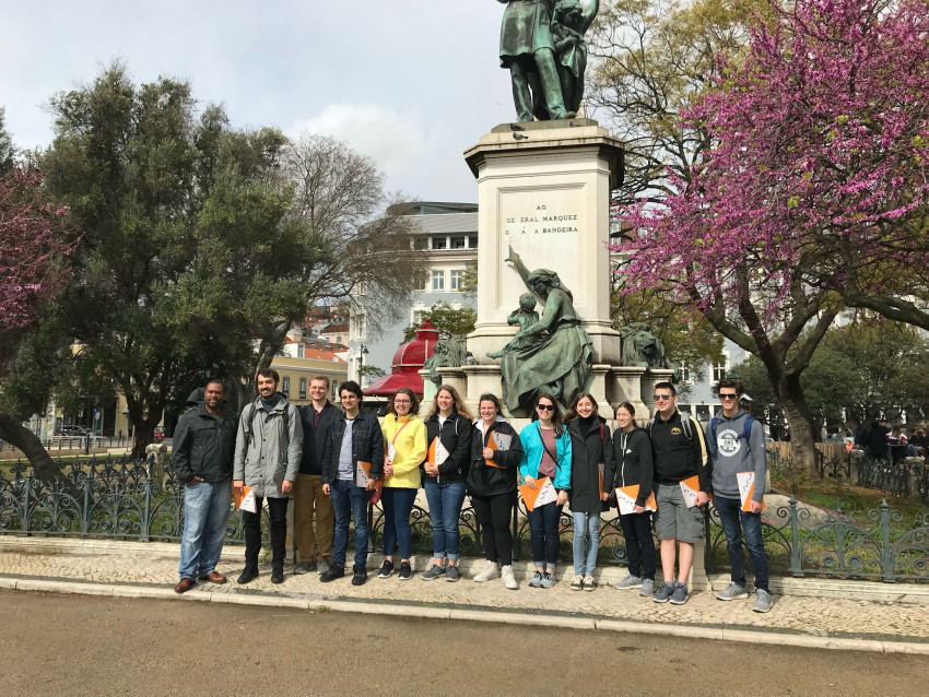 A group of students stands in front of a statue in Portugal.