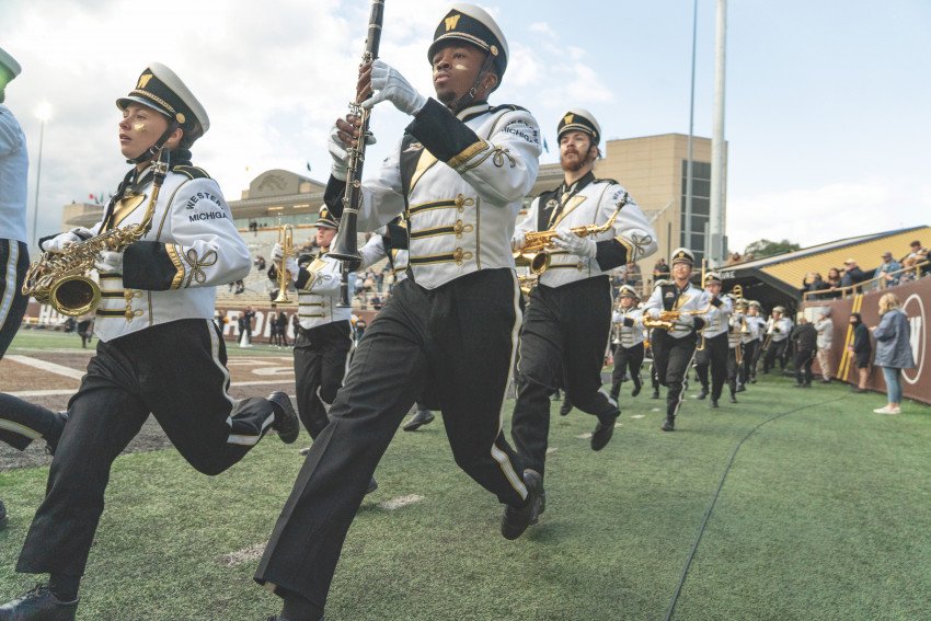 Marching band members run with their instruments.
