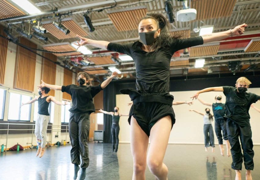 Tsai Hsi Hung dances with her arms outstretched in front of a class full of students.