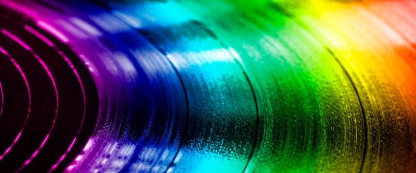 A close-up view of the grooves in a record in the hues of the rainbow.