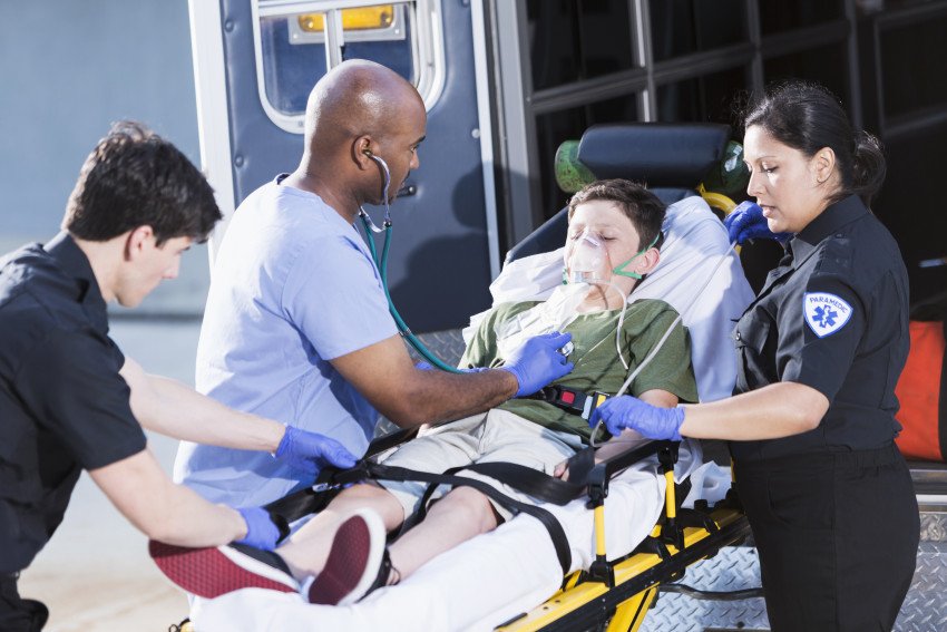 Paramedics tend to a child on a stretcher.
