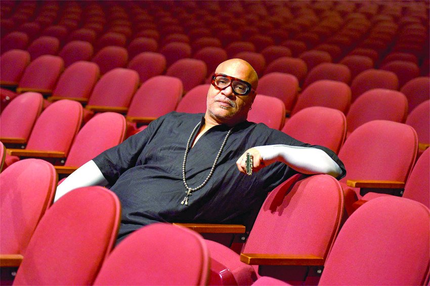 M. Scott Johnson sits on the red seats of an empty theatre.