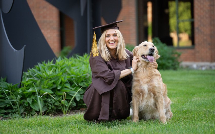 Taylor Ernst poses in her cap and gown alongside her golden retriever, Muffin. 