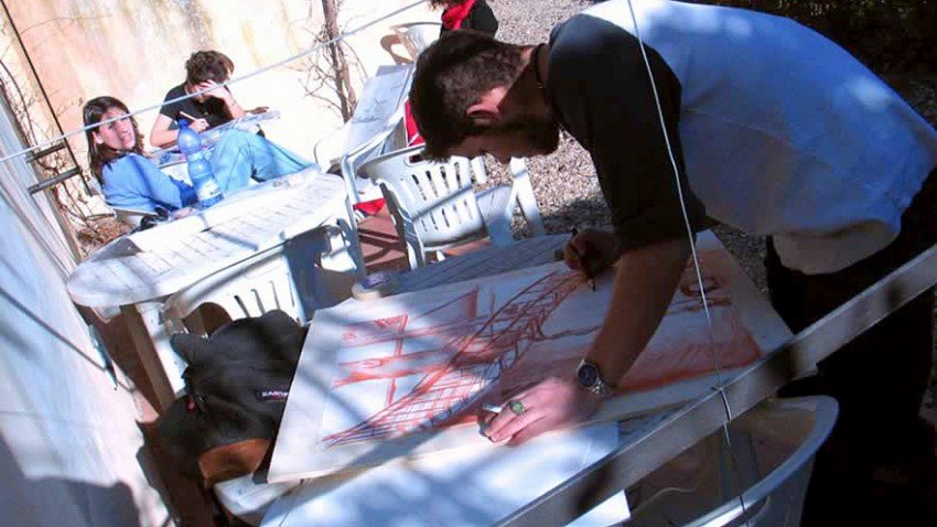 Photo of a student drawing a sketch in an outdoor cafe.