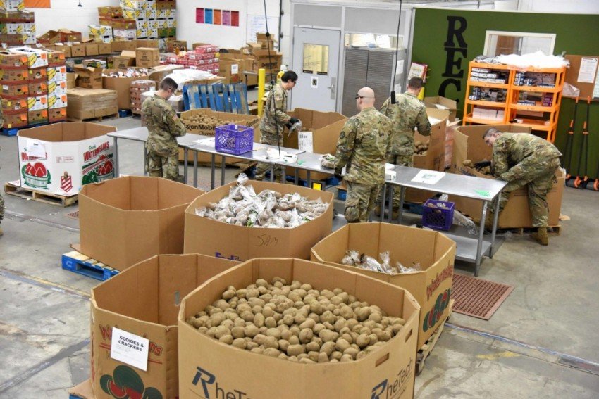 National Guardsmen pack boxes of food in a warehouse.