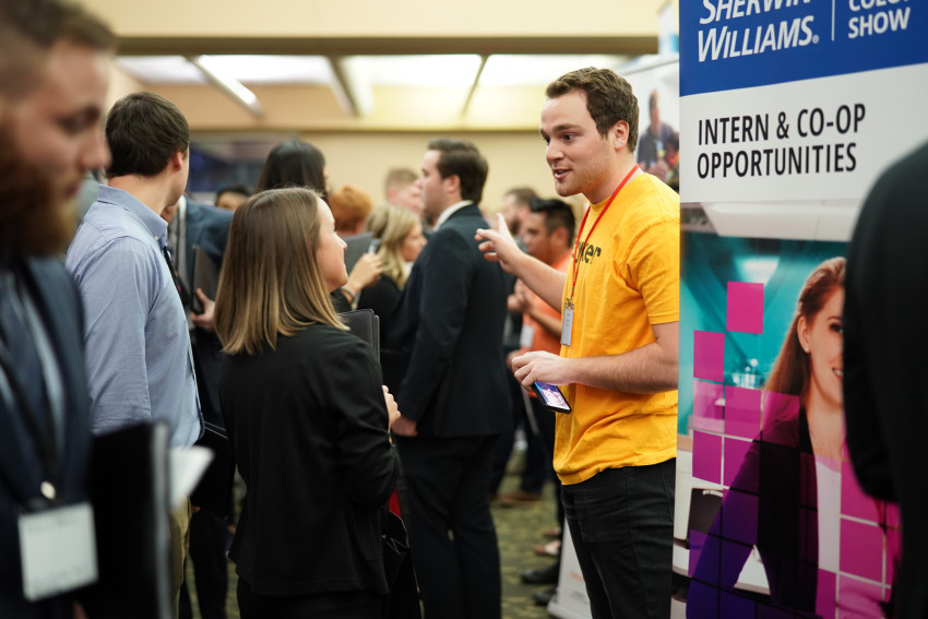 An employer speaking to a student at a career fair.