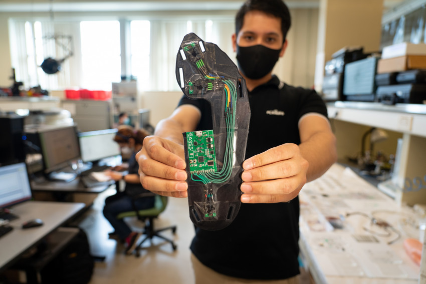 A student holds up a sensor that sits in the bottom of a boot.