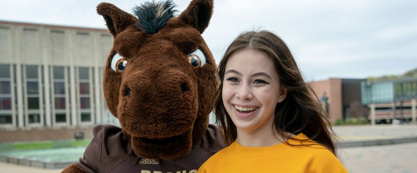 Buster Bronco and a student smiling.