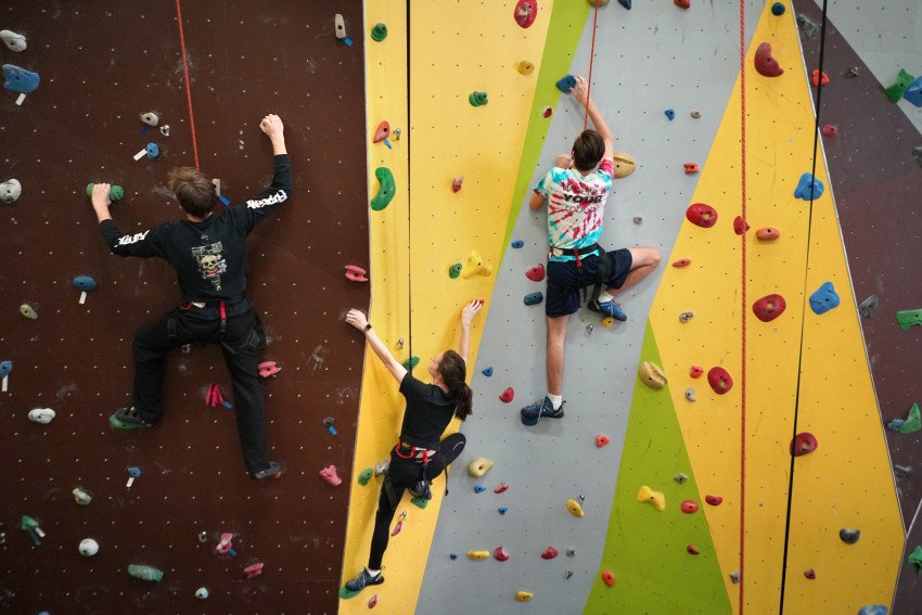 Students climbing up a rock-climbing wall.