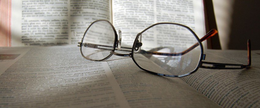 Photo of dictionary with reading glasses.