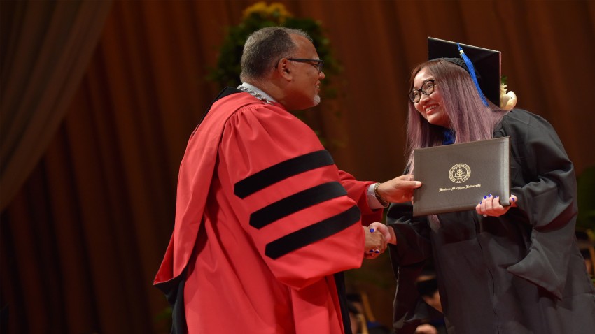 president montgomery shakes the hand of a graduate on stage
