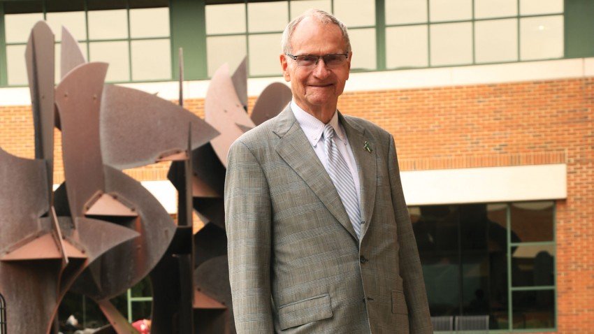 Photo of Dave Rozelle in professional dress in front of sculptures at Schneider Hall.