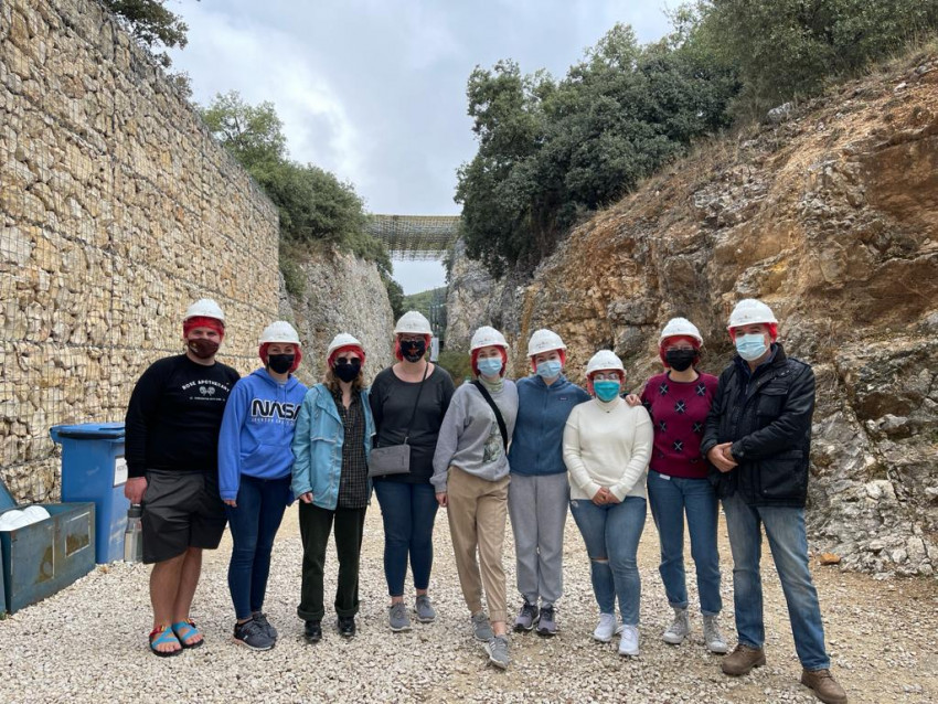 Students in masks and hard hats standing in front of Atapuerca archeological site.