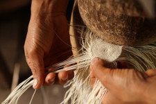 Hands weaving the crown of a Panama hat.