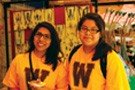 Two students wearing yellow shirts with brown "W" logo smiling and posing for a photo.