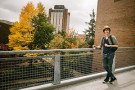 Student standing by railing in front of fall scenery