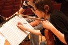 Female violinist writing notes on her music.